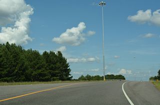 A loop ramp from a distributor roadway along I-59 southbound forms the eastbound beginning of Interstate 759. Traffic merges onto a roadway adjacent to a roadway stub onto a bridge slated for two lanes, but striped for one.