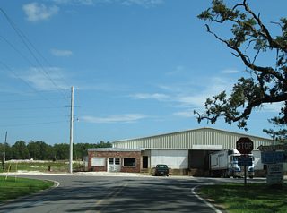 CR 10 (Bon Secour Highway) concludes at River Road opposite a marine facility on the Bon Secour River. River Road spurs west and east along the waterway.
