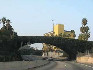 Overtaking the Santa Monica Freeway, SR 1 continues with its most common appellation once again: the Pacific Coast Highway. Traveling below grade, a barrier median separates the four lane freeway at the Main Street over crossing. The concrete arch bridge was built in 1925 as an overpass to Olympic Boulevard, which preceded SR 1 along this stretch.