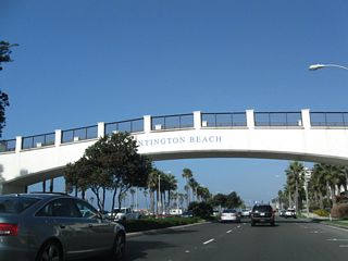 This arch bridge allows pedestrians to cross over the Pacific Coast Highway safely; some pedestrians are beachgoers from the nearby Hyatt Regency Hotel.