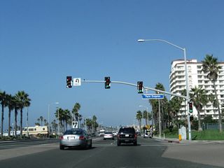 Northbound California 1 (Pacific Coast Highway) meets Twin Dolphin Drive. The towering Waterfront Hilton comes into view ahead on the right.
