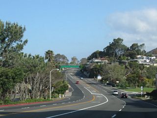 California 1 descends into the valley formed by Aliso Creek. The concrete T-beam arch bridge spanning the creek at Aliso County Park was built in 1926 and widened in 1932.
