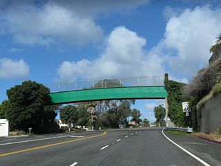 A 1929 pedestrian over crossing bridge spans SR 1 north beyond Aliso Creek and Country Club Drive.