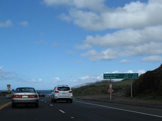 California 1 leaves Laguna Beach near Emerald Bay and enters Crystal Cove State Park. A mileage sign provides the distance to Newport Beach (four miles) and Long Beach (28 miles).