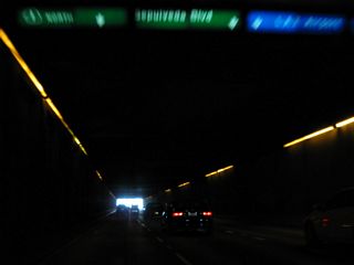 An internally lit overhead guide sign shows the lane allocation for California 1, Sepulveda Boulevard, and the airport.