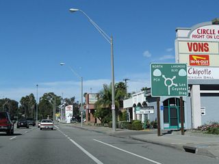 After the traffic signal with Ximeno Avenue, this diagrammatic sign indicates the movements available when using the Los Alamitos Traffic Circle. Proceeding north through the traffic circle, the first right connects to Los Coyotes Diagonal, followed by California 19 (Historic U.S. 91 / Lakewood Boulevard) north and California 1 (Pacific Coast Highway) west.