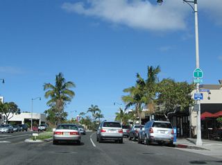 Reassurance marker for SR 1 north posted at Orchid Avenue. Continuing northwest through Downtown Corona del Mar, cross streets are named after flowers, with names descending alphabetically from Poppy Avenue to Acacia Avenue.