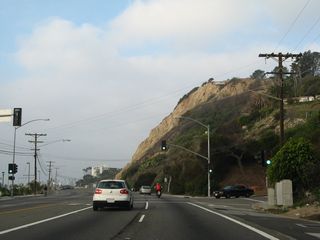 Northbound California 1 (Pacific Coast Highway) reaches the traffic signal for Bay Club Drive, which leads into the Bel-Air Bay Club.