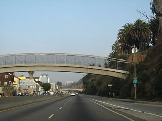 An on-ramp joins the Pacific Coast Highway from the Ocean Avenue at the first of several pedestrian bridges spanning the Pacific Coast Highway in Santa Monica. During peak beach hours, this section of highway can be severely congested.