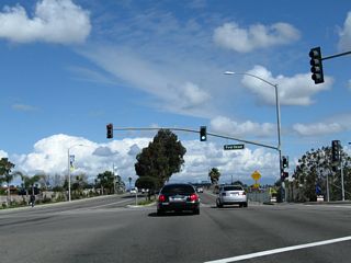 Northbound California 1 (Pacific Coast Highway) approaches its final traffic signal in Orange County, with First Street. Ahead is the sign welcoming motorists into Los Angeles County and the bridge connecting Seal Beach with Long Beach over the San Gabriel River.