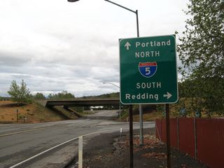 After leaving the signalized intersection with Main Street, eastbound Moonlit Oaks Drive approaches Interstate 5 at Exit 773. The first right turn connects to Interstate 5 south to Weed, Mount Shasta, and Redding. The first left turn connects to Interstate 5 north to Ashland, Medford, Grants Pass, and Portland.