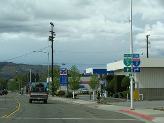 Business Loop I-5, Historic U.S. 99, and California 3 (Main Street) skirt the eastern edge of downtown Yreka. Here, California 3 approaches an intersection with Center Street, which travels one-way eastbound to link up with Miner Street en route to Interstate 5 Exit 775. A shield assembly points the way for Business Loop I-5 (implied to include California 3) north via Main Street and Interstate 5 via Center Street east and Miner Street east.