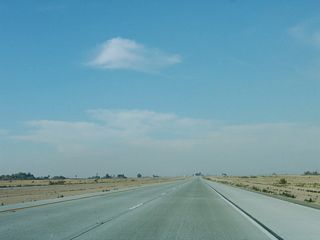 The design features of the California 7 expressway north of California 98 include concrete travel lanes and concrete shoulders, which is not a common feature of most California expressways.