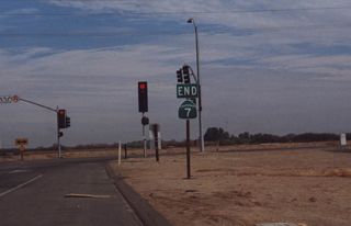This photo shows the former "End California 7" shield assembly that used to exist along northbound California 7 at its intersection with California 98. This end was temporary pending construction of the direct California 7 connection to Interstate 8. California 7 is a relatively new route, commissioned around 1994, that provides access to a new Port of Entry between Mexico and California in the Imperial Valley. Since it parallels California 111, it provides relief to that route and to California 86. Only the segment between the border and California 98 has been constructed (to expressway standards). The remainder of the route was constructed between California 98 and Interstate 8 in 2005. Due to an early lack of funding for this new segment, it was briefly considered for construction as a toll road. However, funding was identified from elsewhere, and the highway opened as a free expressway. Portions of the new alignment of California 7 are located along former Orchard Road. The existing Orchard Road interchange was upgraded to handle expressway traffic.