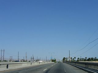 Indio Boulevard eastbound spans the Whitewater River. This concrete tee beam bridge (16 spans) carries the eastbound lanes over the river. It was built in 1925 and was expanded in 1955 to its current configuration. The westbound lanes use a separate, concrete tee beam span that was built in 1956.