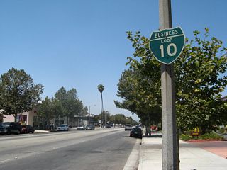 The first reassurance shield for Business Loop I-10 west appears on westbound Holt Avenue after Towne Avenuen. This old sign is wooden, a rarity in California.