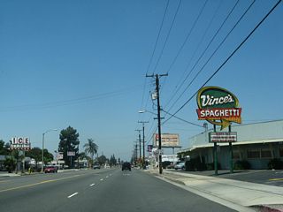 Holt Boulevard transitions into a five lane boulevard west of Mountain Avenue by Vince's Spaghetti and an ice skating rink, both of which are identified by older marquee signs.