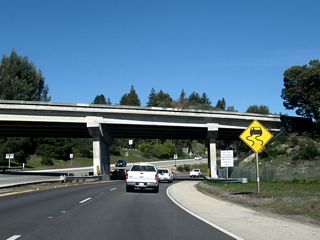 The lanes for California 17 north pass under the California 1 southbound lanes. A begin freeway sign is posted as California 17 begins its journey north. This interchange is known as the Fishhook Interchange due to the loop ramp that carries California 1 north (west) through here. No loop ramp is required for through traffic on California 17 or for traffic on California 1 south (east). At the time this photo was taken, there was some construction on California 17 at the California 1 interchange in Santa Cruz.  This is part of the "Highway 1/17 Widening for Merge Lanes" improvements, which will add merge lanes on both California 1 and California 17 in the vicinity of the Fishhook interchange, as well as reconstruct various ramps at the California 1/California 17, California 1/Emiline Street, and California 1/Morrissey Boulevard interchanges.  Construction started in April 2007, and was expected to last through Spring 2009.¹