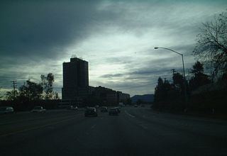Silhouetting of the skyline is the city of Campbell's PruneYard office and shopping complex as seen from California 17 south near Milepost 24. The PruneYard was built sometime in 1964 and for a long time was the tallest building between San Francisco and Los Angeles. Despite being a landmark, they may look a bit out of place, since few other high rise complexes are located near here or are visible from California 17. The nearest high rises are in downtown San Jose, off of California 87 and Interstate 280. Many thanks to David Friedland assisting with PruneYard information.