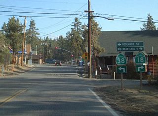 Southbound California 18 and California 38 approach their southern junction in Big Bear City. California 18 turns right (west) toward Lake Arrowhead, while California 38 turns left (east, south, then west) toward Redlands via the national forest.