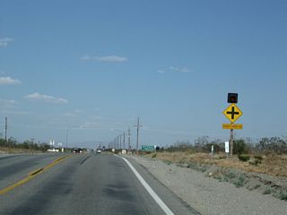 Eastbound California 18 (Palmdale Road) approaches Sheep Creek Road, which travels south to Phelan and ultimately connects to California 138. Turn left here for Sheep Creek Road north to El Mirage.