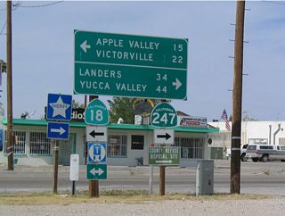 As this signage shows, California 18 makes a left turn upon entering Lucerne Valley. This signage implies that California 18 actually meets California 247, but in reality, they do not meet. To get to California 247 north/south, motorists on California 18 must turn right onto this connector road. Note that both destinations for California 247 (Yucca Valley and Landers) are found along southbound. Landers was made famous in 1992 when an earthquake struck there, causing damage to some of the ubiquitous limestone quarries scattered about the region.