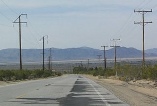Upon reaching the base of the San Bernardino Mountains and exiting the San Bernardino National Forest, California 18 emerges in the high desert of Mojave. The two-lane highway passes by several limestone quarries, several of which are visible from great distances because they are located on the face of the mountains. In fact, the power lines on the west side of the highway primarily provide power to those limestone mining facilities.