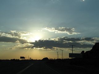 The daytime headlight requirement section ends along westbound California 18 as we crest at this slight rise. A beautiful sunset was in the making on this early summer's evening, mostly due to monsoonal moisture bringing clouds into the area.