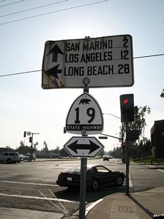 Westbound Huntington Drive meets California 19 (Rosemead Boulevard). Prior to 2008, a white guide sign placed by the Automobile Club of Southern California (ACSC) still directed traffic at this intersection. Mounted below the mileage sign was a replica of a white California 19 bear shield. Both of these signs are now gone.