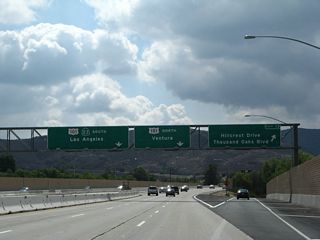 Southbound California 23 reaches Exit 13, Hillcrest Drive and Thousand Oaks Boulevard. The next exit is the junction with U.S. 101, a freeway-to-freeway interchange. Stay left for U.S. 101 and California 23 south. In the distance ahead lie the Santa Monica Mountains, which separate Thousand Oaks from the Pacific Ocean and Malibu. The Moorpark Freeway comes to a close here.