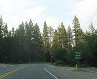 Eastbound California 28 approaches the the left turn to Rocky Ridge Road north to Burton Creek State Park. This park is primarily for hiking, as the park is largely undeveloped and is situated away from the lake.