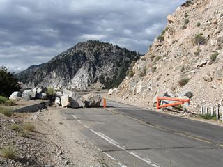 Fallen rocks and the orange gate prevent access to the closed segment of state route.