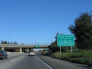 To Fresno International Airport, motorists are advised to use California 180 east according to this sign on northbound California 41. California 180 is a major east-west freeway that crosses the city of Fresno; the interchange between California 41 and California 180 was built in 1974.