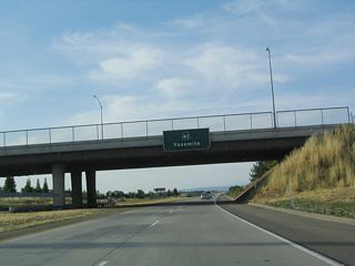 An overhead pull-through sign for California 41 (Eisenhower / Yosemite Freeway) north is posted on the Audubon Drive overpass. The control city remains "Yosemite." Soon thereafter, California 41 crosses the San Joaquin River, leaves the city and county of Fresno and enters Madera County.