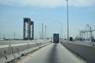 Coordinated by Alameda Corridor Transportation Authority, the Port Access Expressway project replaced the previous lift bridge crossing Cerritos Channel. The replacement Commodore Schuyler F. Heim Bridge is a concrete, seven-lane wide span. The original lift bridge along the Terminal Island Freeway here opened to traffic on January 10, 1948.