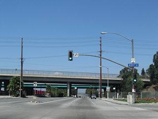 A viaduct takes 223rd Street over Alameda Street beyond this signalized intersection with the access road joining the two urban arterials.