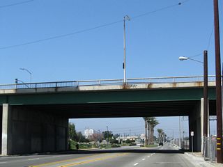 The California State Route 47 designation along Alameda Street ends at the grade separation with SR 91. Artersia Boulevard spans the arterial to the immediate north.