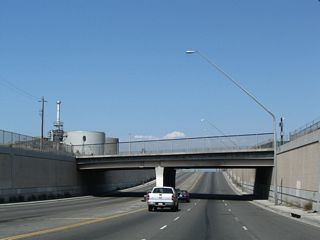 Maintaining six overall lanes, Alameda Street drops below a railroad bridge north of O Street.