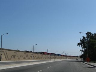 Heading south ahead of Homestead Place, Alameda Street leaves Compton and enters unincorporated Rancho Dominguez. The Mid-Corridor Trench runs along the east side of Alameda Street.