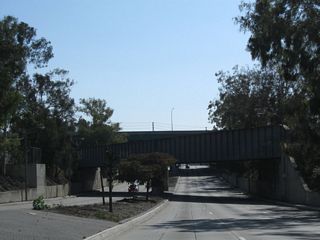 A railroad overpass and Interstate 405 span a below grade section of Alameda Street south ahead of 223rd Street.