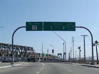 Henry Ford Avenue crosses Dominguez Channel ahead of Pier A Way and the entrance ramp taking SR 47 south into SR 103 (Terminal Island Freeway).