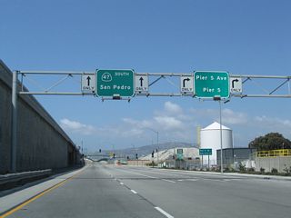 SR 47 westbound intersects Pier S Avenue north to New Dock Street adjacent to the elevated roadway connecting I-710 south with Ocean Boulevard west.