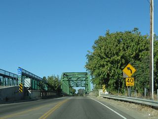 Northbound Manthey Road (Old U.S. 50 / Lincoln Highway) crosses a Pratt through truss bridge to pass over the San Joaquin River. Built in 1926, the bridge has a newer, parallel pedestrian/bicycle bridge alongside it and extends for about 539 feet in length with a 15'3" vertical clearance from the bridge deck. This area is not far from Mossdale Crossing. A parallel span to allow for a four-lane U.S. 50 through here was built in 1949; today, this second span is still in use as part of the transition ramp from California 120 west to Interstate 5 south and Interstate 205 west.