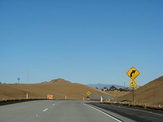 Two lanes carry the transition ramp from California 54 (Filipino-American Highway) east to Toll California 125 south. The freeway interchange is situated adjacent to Sweetwater Dam.
