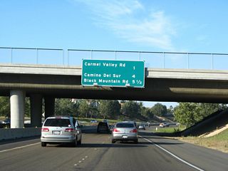 This mileage sign provides the distance to the next three exits along California 56 (Ted Williams Freeway) east: Exit 3, Carmel Valley Road; Exit 6, Camino del Sur; and Exit 7, Black Mountain Road. In 2002, there was no mileage sign, and an "end freeway" temporary sign was posted prior to the Carmel Country Road overpass.