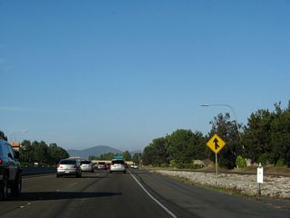Traffic from Carmel Country Road merges onto eastbound California 56. In 2002, more signs announced the temporary end of the freeway. Prior to July 2004, traffic was forced to exit onto Old Carmel Valley Road, which used to connect with the freeway and continue as a two to four-lane surface street across Pacific Highlands Ranch and Torrey Highlands into Rancho Penasquitos via Black Mountain Road. Carmel Valley Road was realigned in 2004 to its present alignment, and there is now no connection to Old Carmel Valley Road from California 56. In the 2002 photo, note how the freeway stub continued to go straight, even though traffic was forced to exit.