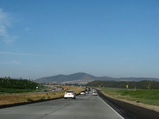 Following scenic Los Penasquitos Canyon and McGonigle Canyon, California 56 passes through some undeveloped areas. While plans call for residential and commercial construction on the north side of the freeway, some of the canyons on the south side of the freeway are planned to remain as open space. In the distance, Black Mountain comes into view.