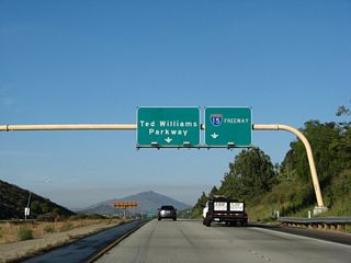 Only the right lane will connect to Interstate 15 south and north. Both movements require passing through traffic signals, so neither connection is freeway-to-freeway. Note the pull through sign of Ted Williams Parkway, which has the California 56 east shield covered by a green overlay.