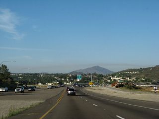 A lone bicyclist uses the California 56 bike lane. There is room southwest of the Interstate 15 and California 56 interchange to eventually create a freeway to freeway connector,  but that does not exist currently.