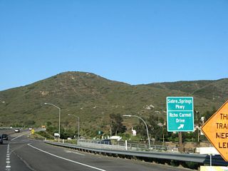 Eastbound Ted Williams Parkway meets the off-ramp to Sabre Springs Parkway and Rancho Carmel Drive. Continue east on Ted Williams Parkway toward the city of Poway.